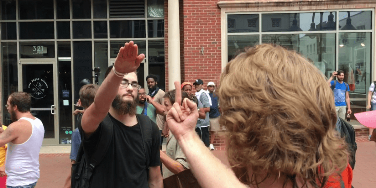 Il saluto fascista di un simpatizzante del terrorismo cristiano USA, cui risponde una donna, di spalle, mostrandogli il dito medio